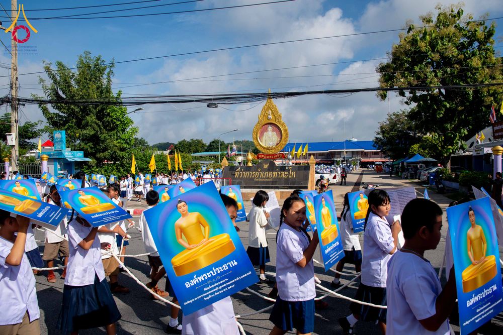 กลุ่มนักเรียนถือป้ายภาพพระพุทธรูปเดินขบวนในงานพิธี