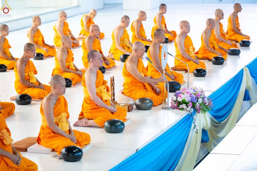พระภิกษุสงฆ์จำนวนมากนั่งสมาธิบนพื้นภายในอาคารเพื่อประกอบพิธีทางศาสนา