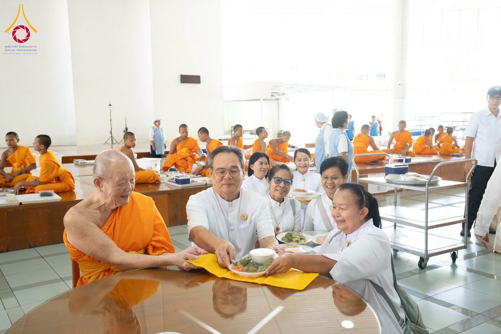 พระภิกษุและพุทธศาสนิกชนในชุดขาวกำลังร่วมพิธีถวายภัตตาหารภายในหอฉัน