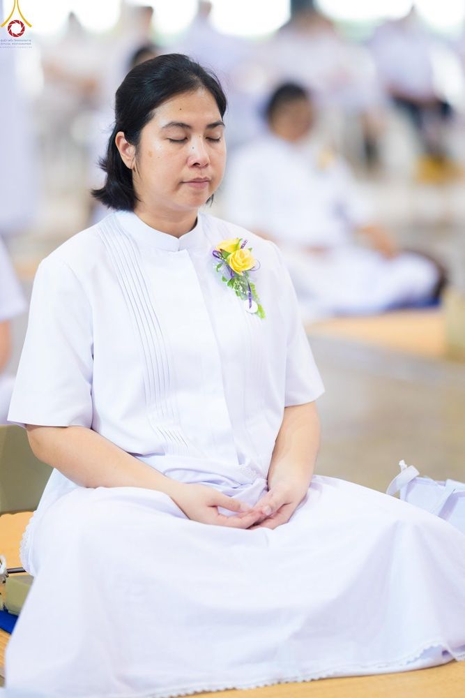 หญิงสาวสวมชุดขาวนั่งหลับตาทำสมาธิอย่างสงบในสถานที่ปฏิบัติธรรม