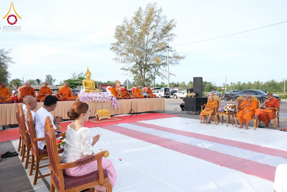 พุทธศาสนิกชนนั่งพนมมือร่วมพิธีตักบาตรพระสงฆ์กลางแจ้งริมหาด