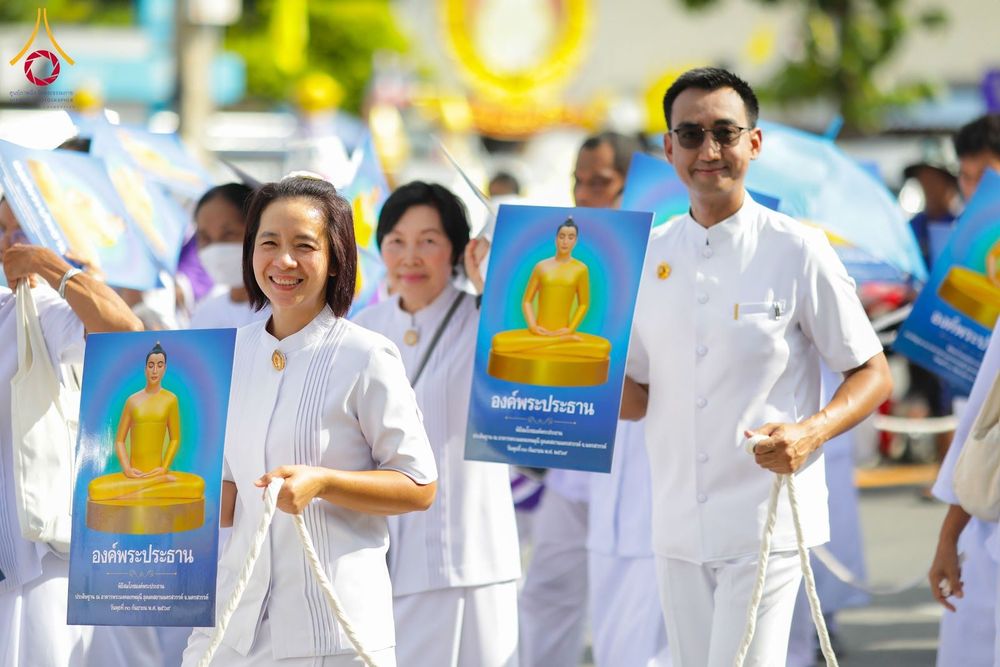กลุ่มคนสวมชุดสีขาวถือป้ายภาพพระประธานในขบวนแห่ทางศาสนา