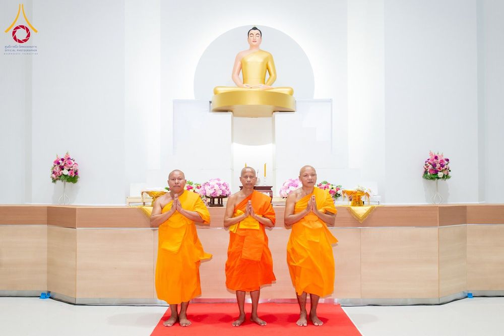 พระภิกษุสงฆ์ 3 รูปยืนพนมมืออยู่หน้าองค์พระพุทธรูปสีทองภายในอาคาร