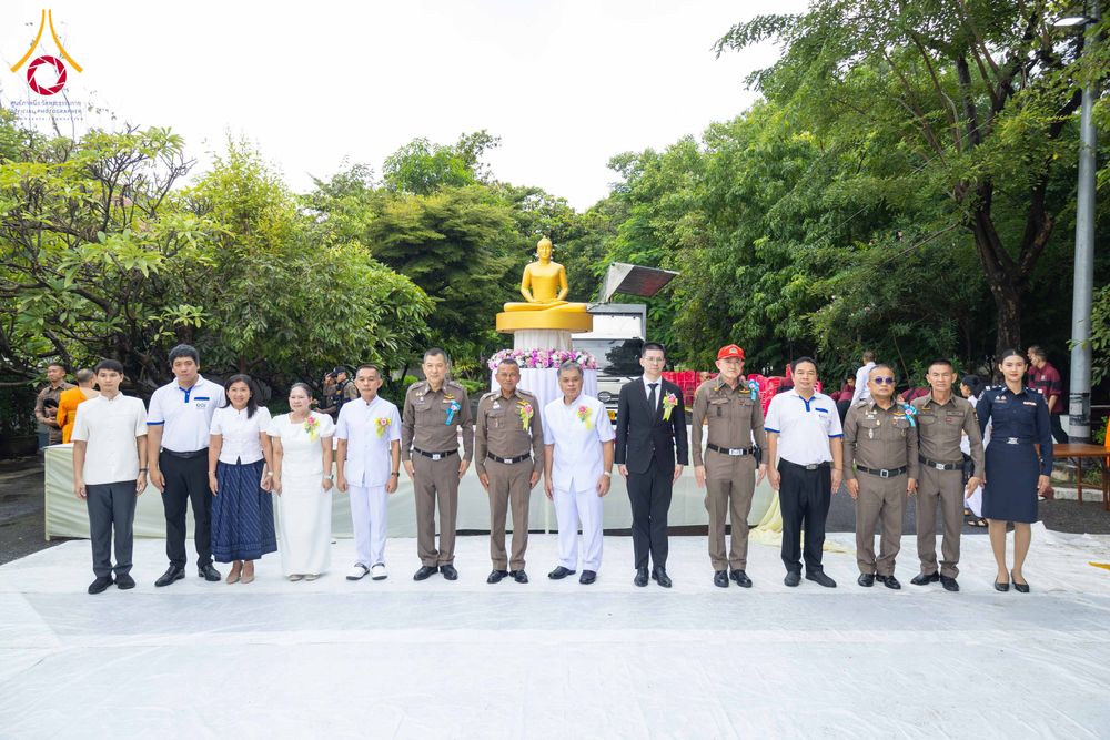 กลุ่มเจ้าหน้าที่ตำรวจและบุคคลทั่วไปยืนเรียงแถวถ่ายภาพร่วมกันหน้าพระพุทธรูปในพิธีตักบาตร