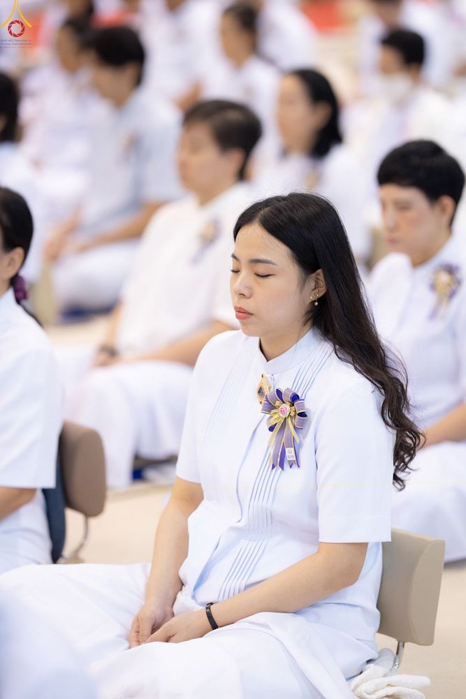 กลุ่มคนสวมชุดสีขาวนั่งหลับตาทำสมาธิในพิธีทางศาสนา