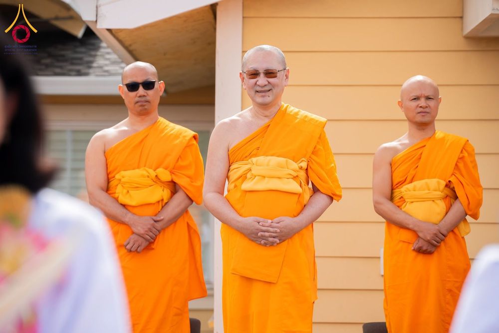 พระภิกษุสงฆ์ 3 รูปยืนเรียงแถวหน้าอาคารในพิธีทางศาสนา