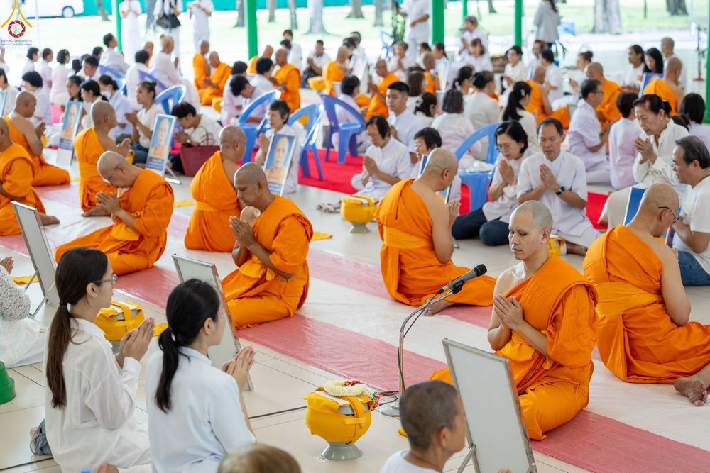 พระภิกษุและสาธุชนนั่งพนมมือร่วมพิธีบรรพชาอุปสมบทหมู่ภายในอาคาร