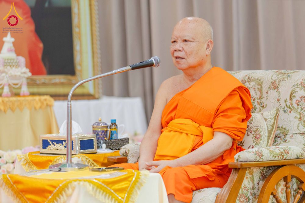 พระภิกษุสงฆ์ครองจีวรสีส้มกำลังนั่งพูดผ่านไมโครโฟนในงานสัมมนา
