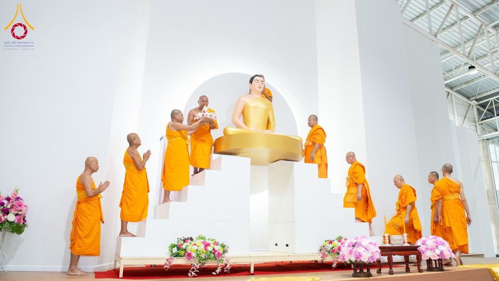 พระสงฆ์หลายรูปกำลังประกอบพิธีทางศาสนาหน้าองค์พระพุทธรูปประธานสีทองภายในอาคาร