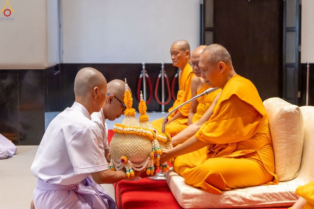 นาคสวมชุดขาวกำลังถวายพานพุ่มดอกไม้แด่พระสงฆ์ในพิธีอุปสมบท
