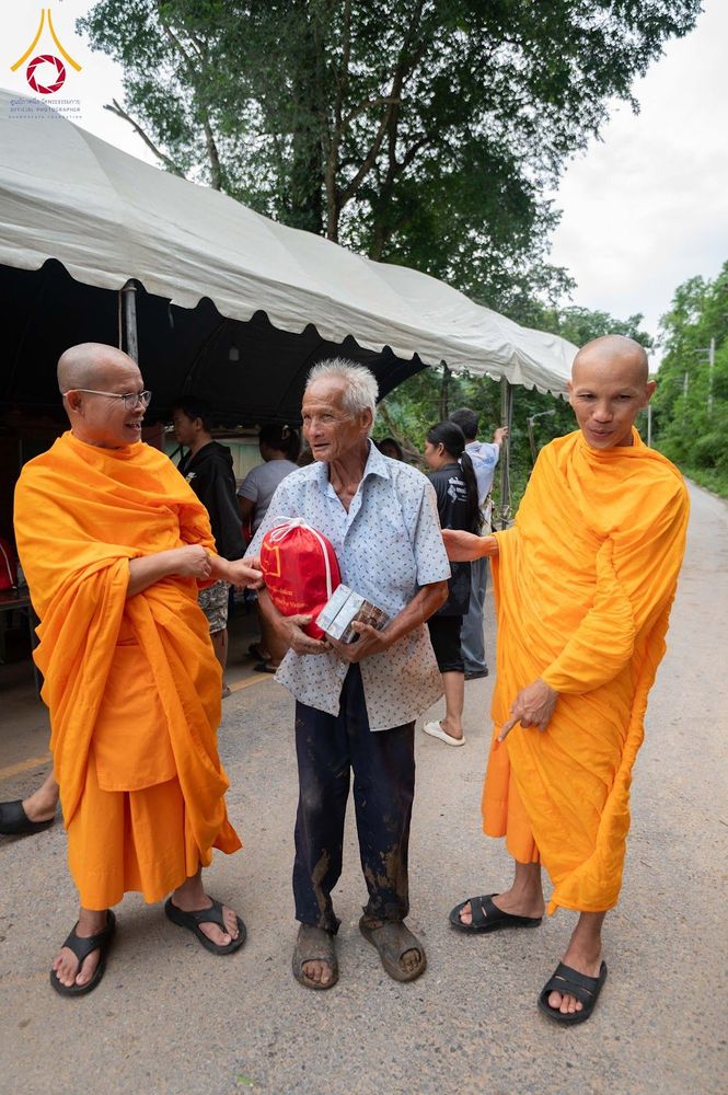 พระสงฆ์สองรูปกำลังส่งมอบสิ่งของช่วยเหลือให้แก่ชายสูงวัยในพื้นที่ประสบภัย
