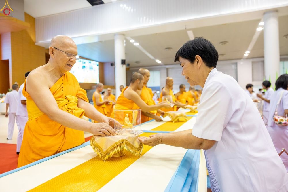 พระภิกษุสงฆ์กำลังมอบพระของขวัญให้แก่พุทธศาสนิกชนในพิธีทางศาสนา