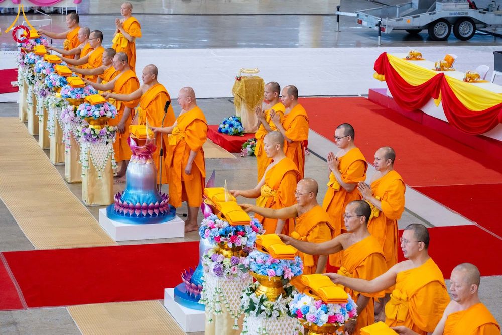 พระภิกษุสงฆ์หลายรูปกำลังประกอบพิธีทางศาสนาโดยวางผ้าไตรบนพานพุ่มดอกไม้ในพิธีทอดผ้าป่า