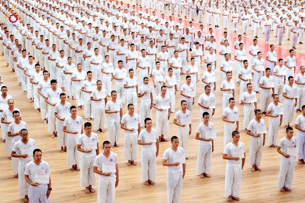 นักเรียนนายสิบตำรวจจำนวนมากสวมชุดขาวถือเกียรติบัตรยืนเรียงแถวในพิธีปิดโครงการบรรพชา