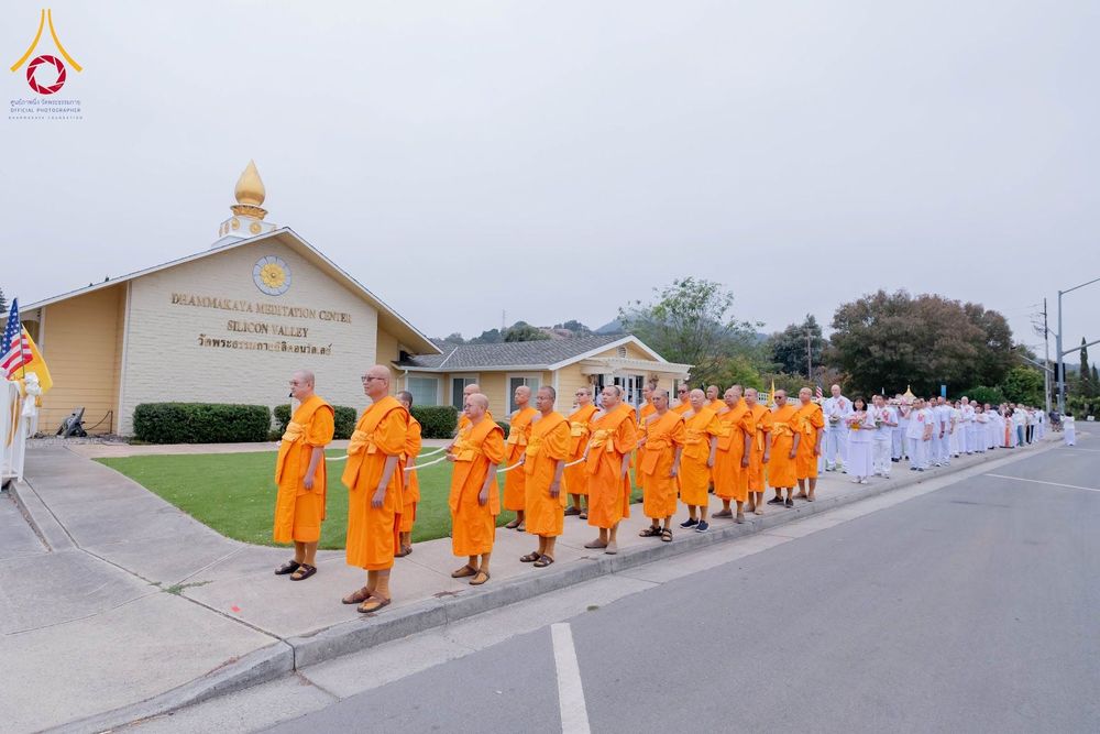 พระภิกษุสงฆ์และพุทธศาสนิกชนเดินแถวเรียงกันบนทางเท้าหน้าอาคารวัดพระธรรมกายซิลิคอนวัลเลย์