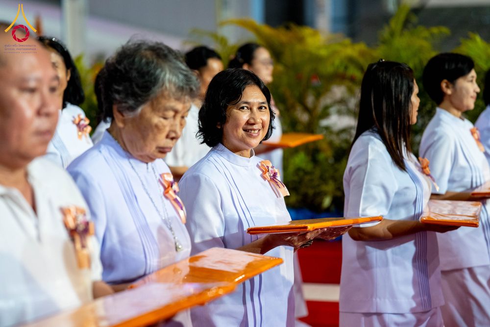 กลุ่มคนสวมชุดสีขาวถือพานผ้าไตรในพิธีทางศาสนา