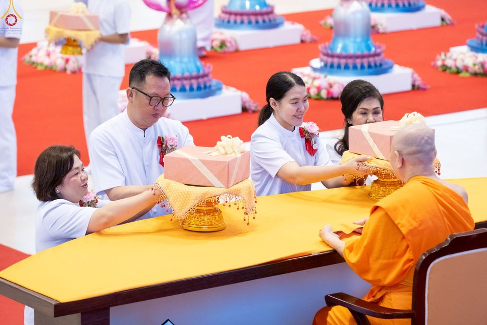 กลุ่มคนในชุดสีขาวกำลังประเคนพานพุ่มผ้าป่าให้แก่พระภิกษุสงฆ์ในพิธีทางศาสนา