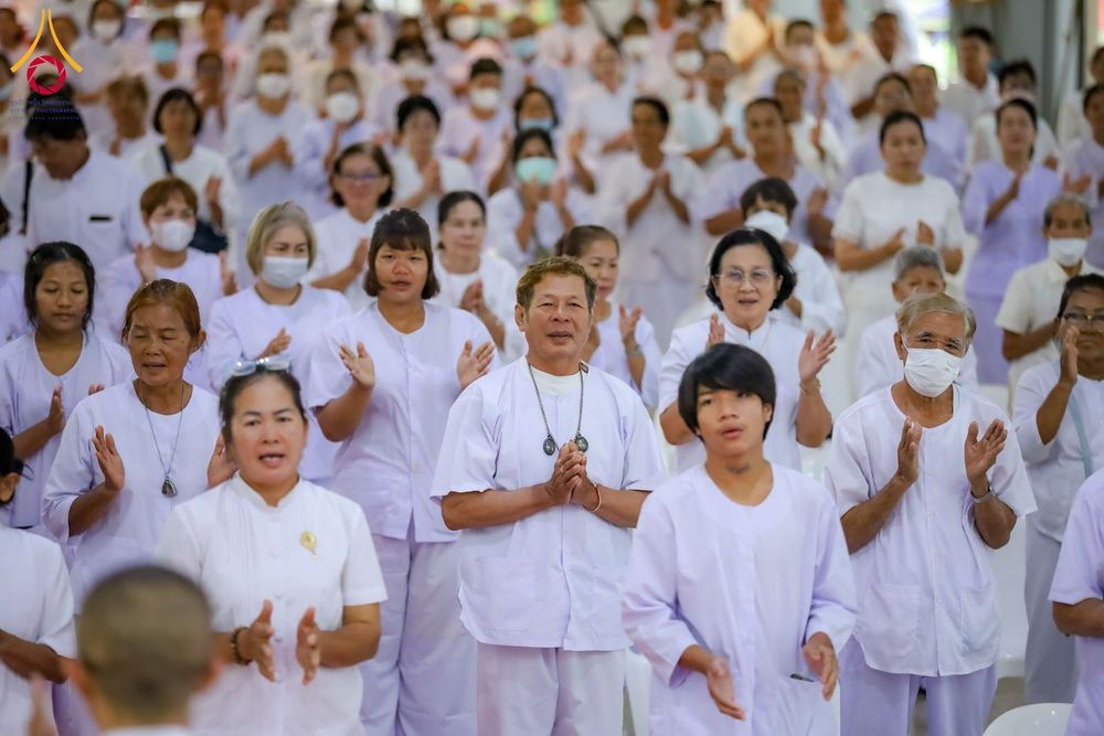 กลุ่มคนสวมชุดขาวพนมมือปฏิบัติธรรมในอาคาร
