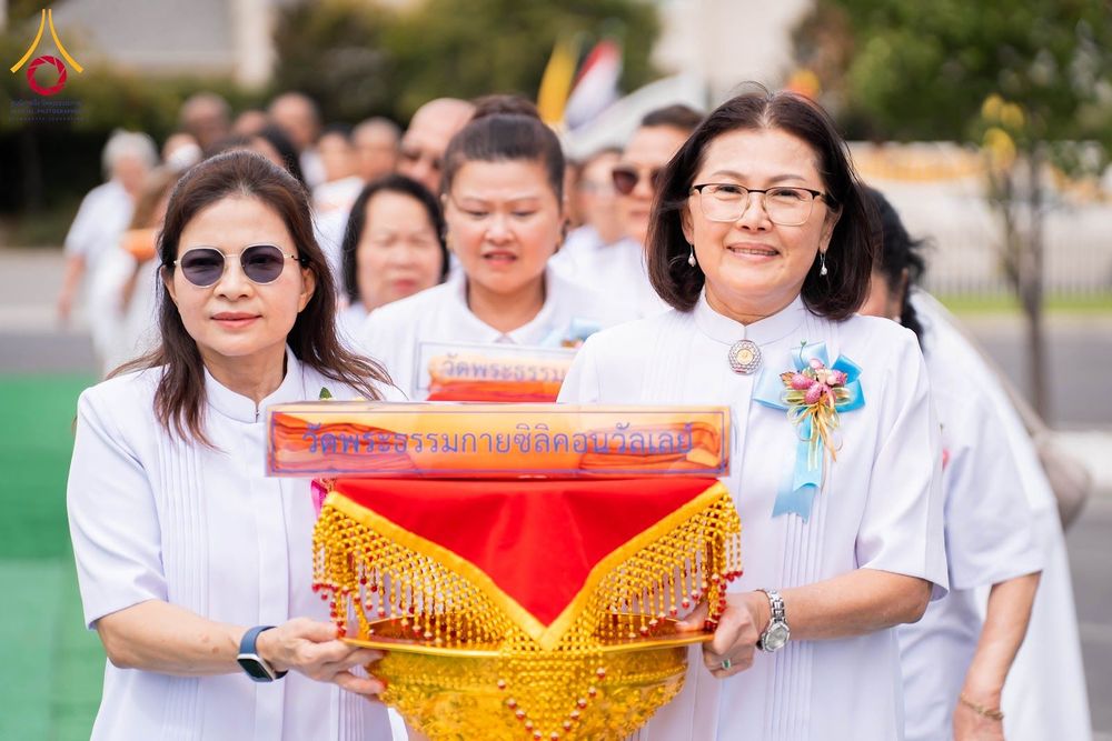 กลุ่มคนสวมชุดสีขาวถือพานพุ่มผ้าไตรจีวรในพิธีทางศาสนา