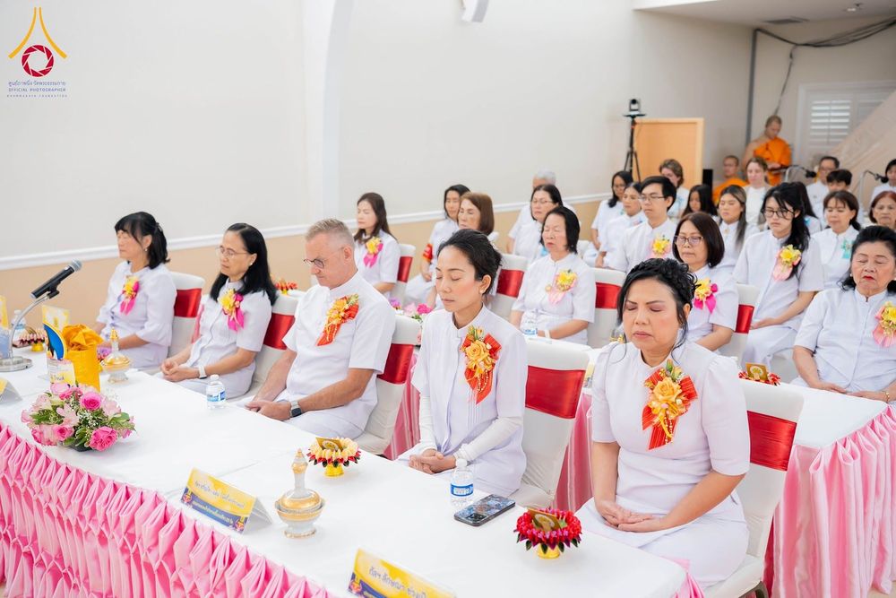 กลุ่มคนสวมชุดสีขาวนั่งทำสมาธิในพิธีทางศาสนาภายในอาคาร
