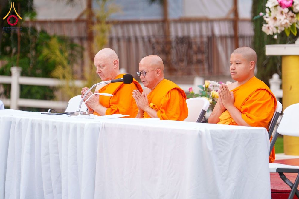 พระภิกษุสงฆ์ 3 รูปนั่งพนมมืออยู่หลังโต๊ะสีขาวในกิจกรรมทางศาสนา