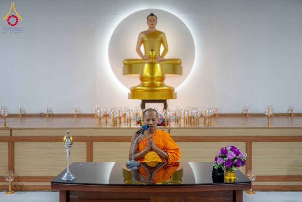 พระภิกษุสงฆ์กำลังนำสวดมนต์หน้าพระพุทธรูปทองคำในห้องอบรม