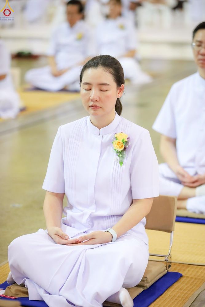 หญิงสาวสวมชุดสีขาวนั่งหลับตาทำสมาธิอย่างสงบในพื้นที่ปฏิบัติธรรม