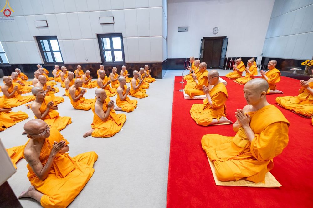 กลุ่มพระภิกษุและสามเณรนั่งพนมมือปฏิบัติธรรมภายในอาคาร