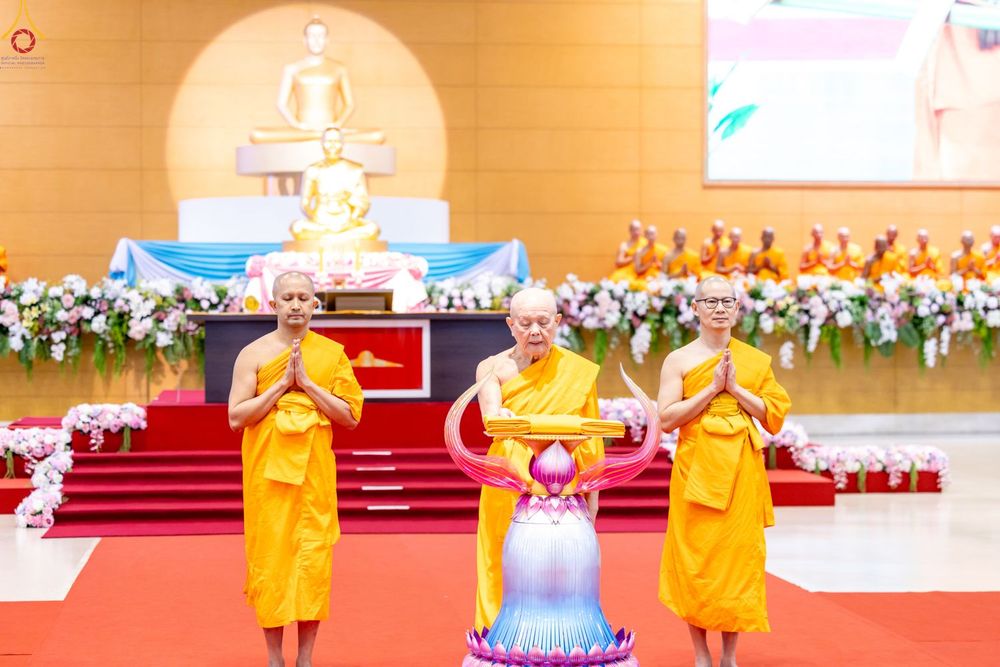 พระภิกษุสงฆ์ในจีวรสีเหลืองทองกำลังประกอบพิธีทอดผ้าป่าหน้าพระพุทธรูปภายในอาคารสภาธรรมกายสากล