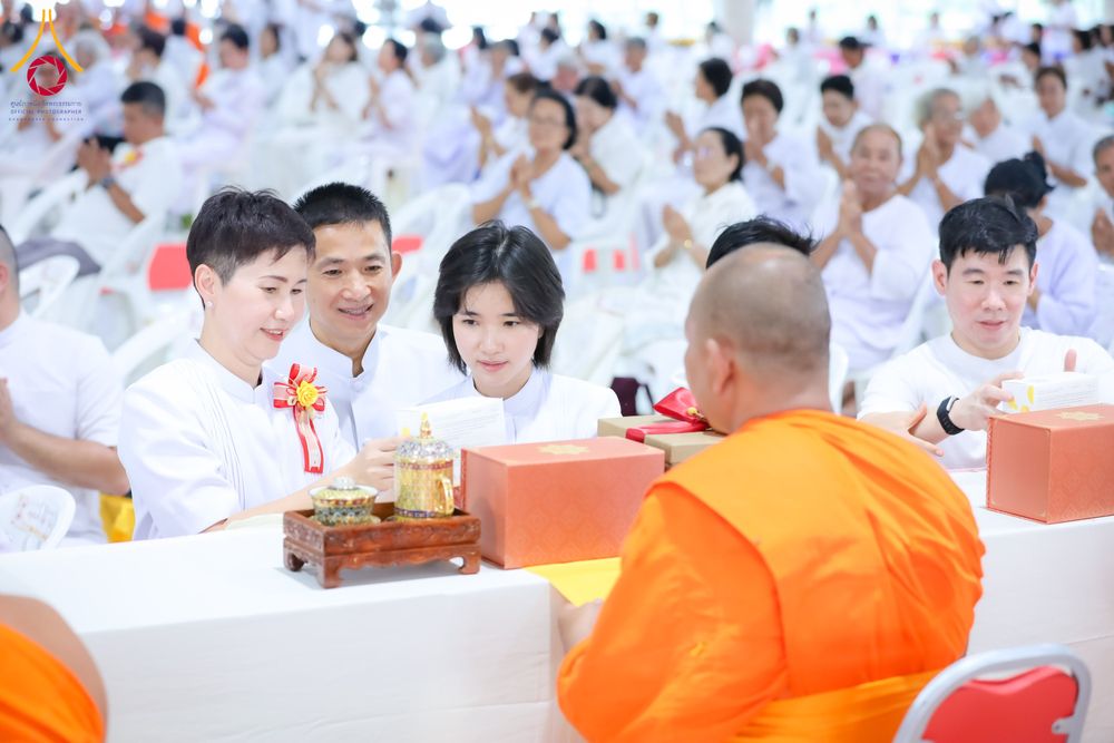 กลุ่มคนในชุดขาวกำลังถวายของแด่พระภิกษุสงฆ์ในพิธีทางศาสนา