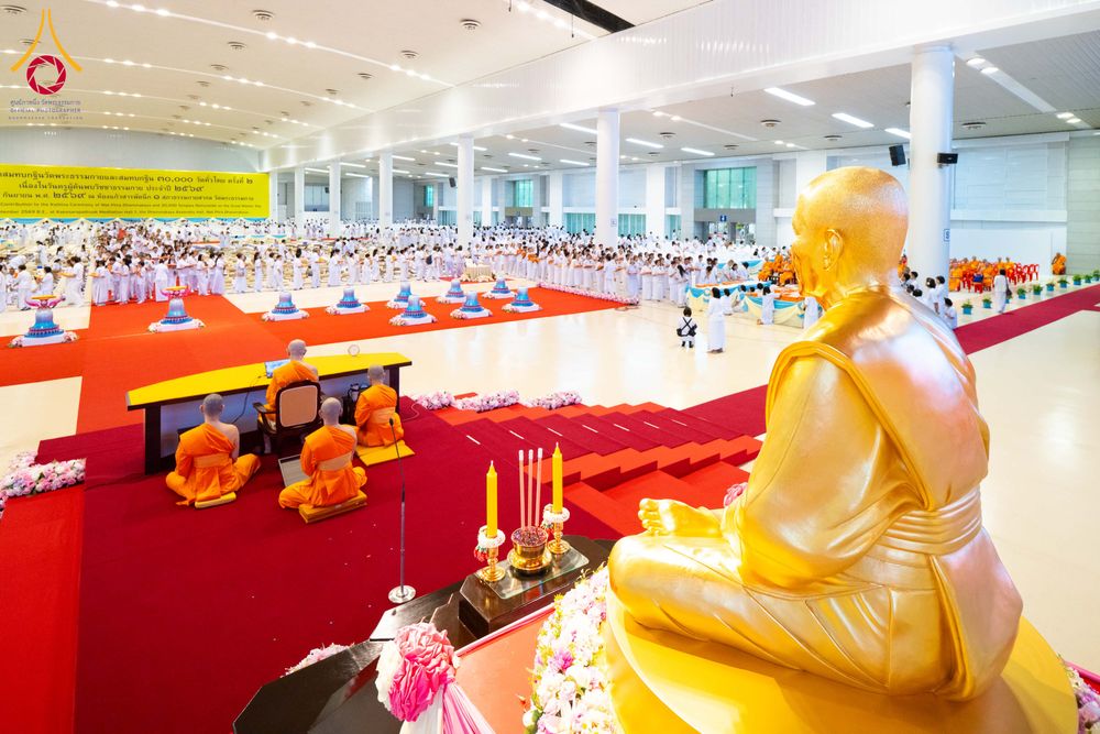 พระภิกษุสงฆ์และสาธุชนจำนวนมากร่วมพิธีทอดผ้าป่าภายในอาคารสภาธรรมกายสากลที่มีรูปหล่อทองคำตั้งอยู่ด้านหน้า