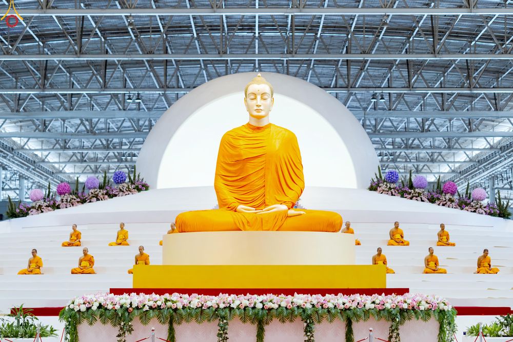 พระพุทธรูปองค์ใหญ่และพระภิกษุสงฆ์นั่งสมาธิในอาคารขนาดใหญ่