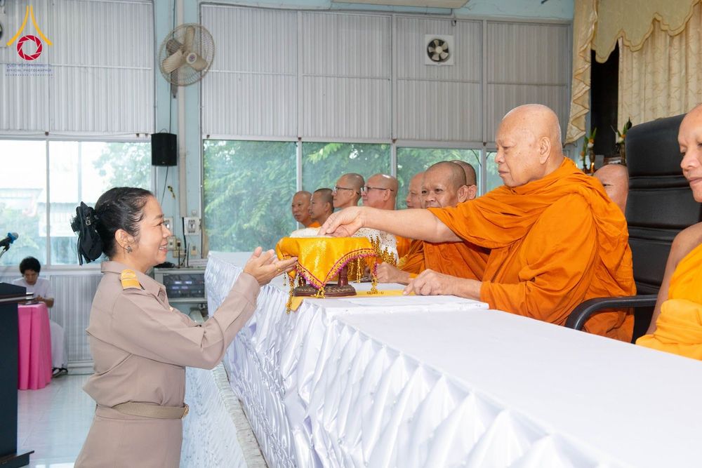 พระภิกษุสงฆ์กำลังประกอบพิธีบรรจุพระบรมสารีริกธาตุลงในพานทอง โดยมีเจ้าหน้าที่หญิงในชุดเครื่องแบบยืนรับด้วยความเคารพ
