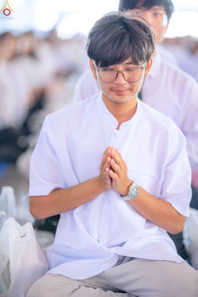 ชายหนุ่มสวมชุดขาวพนมมือไหว้ด้วยความสงบในพิธีทางศาสนา