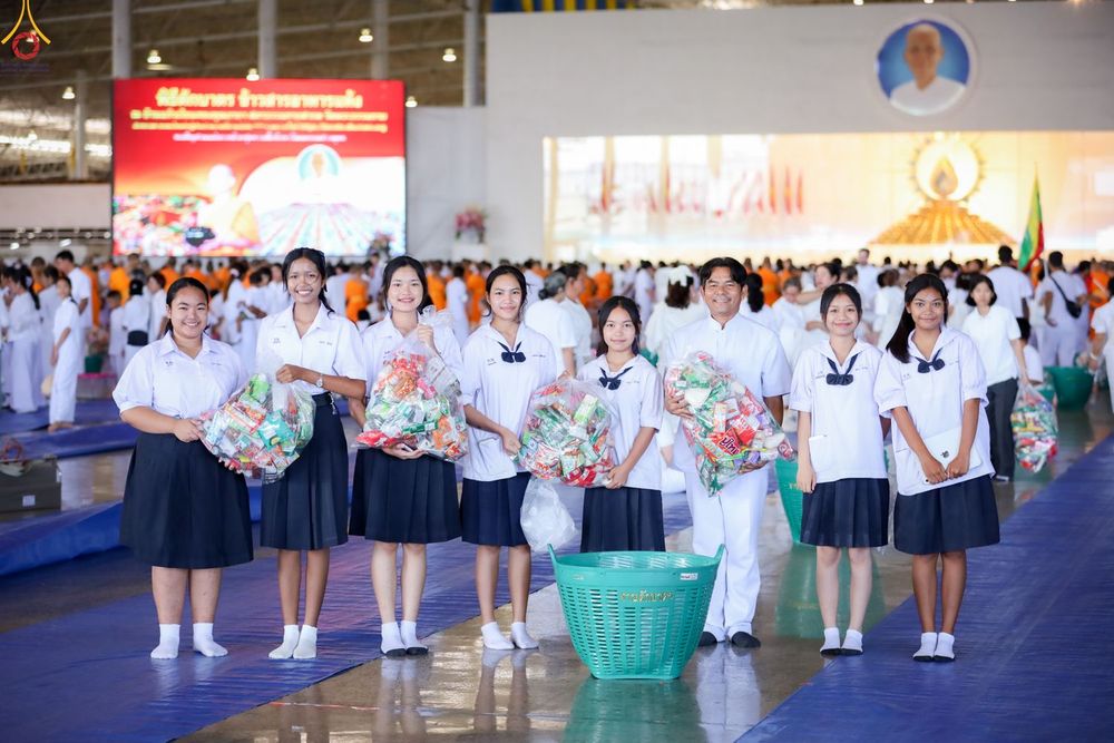 กลุ่มนักเรียนหญิงและชายถือถุงใส่ของแห้งเตรียมตักบาตรภายในสภาธรรมกายสากล
