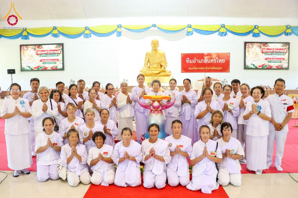 กลุ่มผู้เข้าร่วมโครงการอบรมในชุดสีขาวถ่ายภาพร่วมกันหน้าพระพุทธรูปจำลองภายในอาคาร
