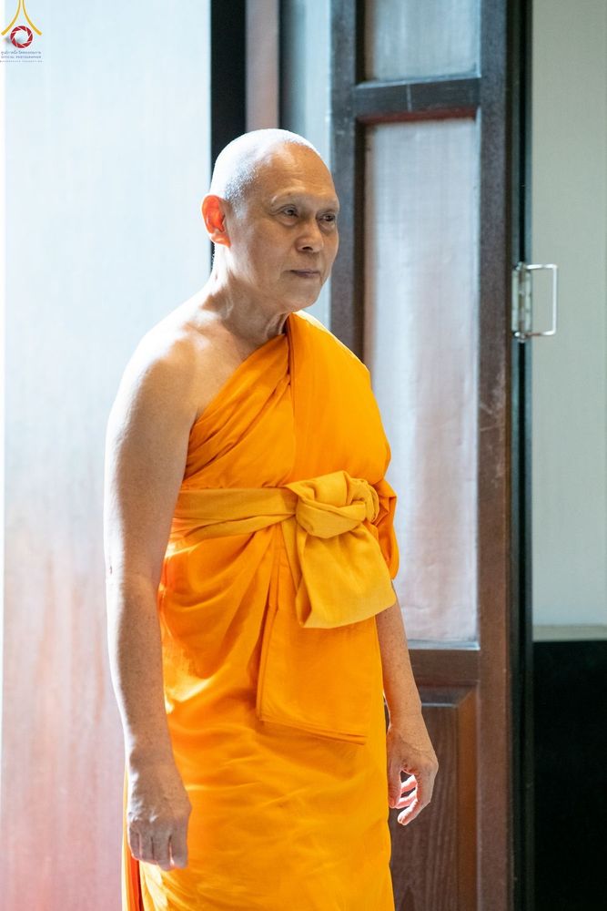 พระภิกษุสงฆ์ครองจีวรสีเหลืองทองยืนอยู่หน้าประตูไม้