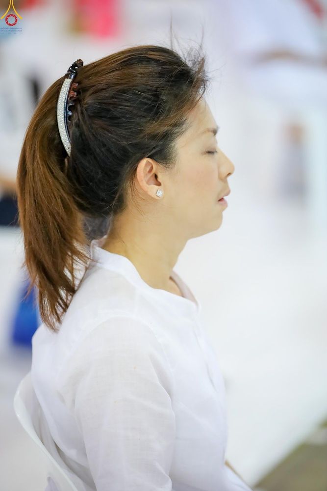 หญิงสาวผมรวบหางม้าสวมชุดสีขาวกำลังนั่งหลับตาทำสมาธิ