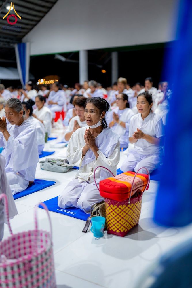 กลุ่มอุบาสิกาแก้วสวมชุดขาวนั่งพนมมือปฏิบัติธรรมภายในอาคาร