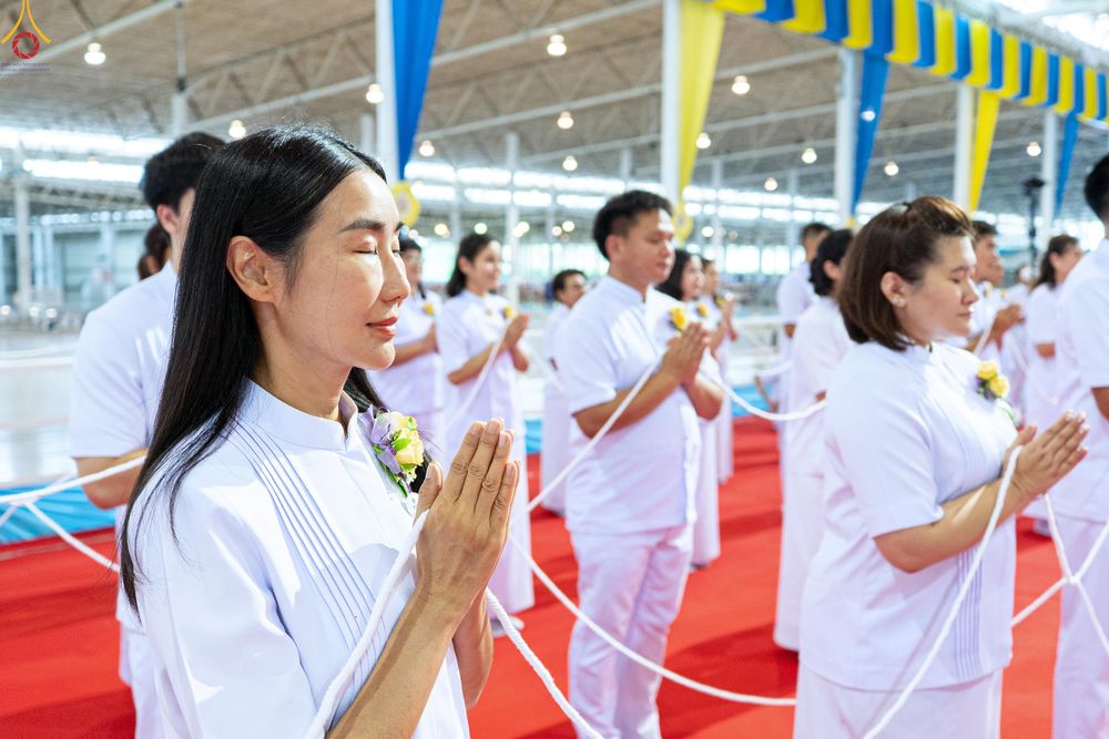 กลุ่มคนสวมชุดขาวประนมมือและถือสายสิญจน์ในพิธีกรรมทางศาสนา