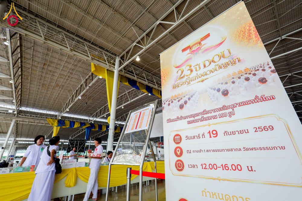 ป้ายไวนิลแสดงรายละเอียดงานครบรอบ 23 ปี DOU และพิธีถวายมหาสังฆทาน ตั้งอยู่ภายในอาคารสภาธรรมกายสากล