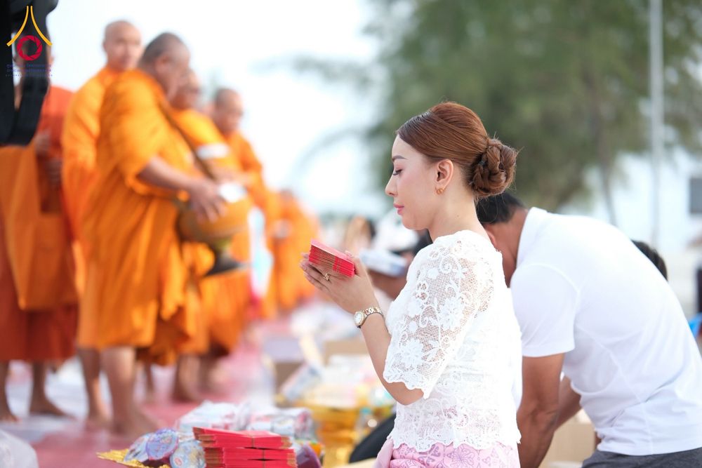 หญิงสาวพนมมือถือซองปัจจัยเตรียมใส่บาตรพระสงฆ์ในพิธีทำบุญ
