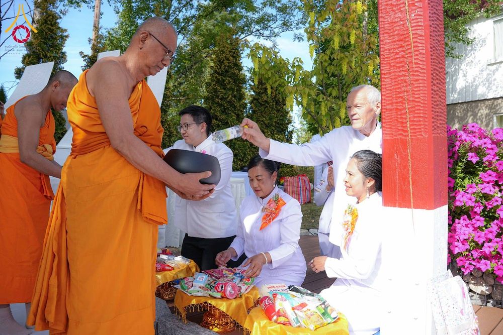 พระภิกษุสงฆ์รับบาตรจากพุทธศาสนิกชนในชุดสีขาวระหว่างพิธีทอดผ้าป่าสามัคคี