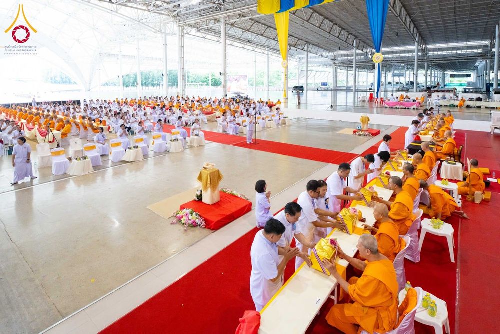 พุทธศาสนิกชนชุดขาวกำลังถวายไทยธรรมแด่พระภิกษุสงฆ์ภายในสภาธรรมกายสากล