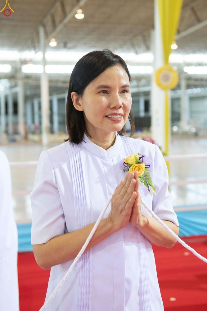 หญิงสาวสวมชุดขาวพนมมือประกอบพิธีกรรมทางศาสนาภายในอาคาร