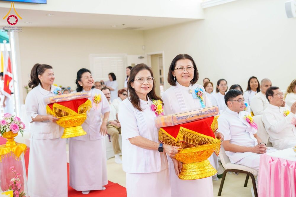 กลุ่มสาธุชนสวมชุดขาวถือพานพุ่มผ้าป่าเดินเข้าสู่พื้นที่ประกอบพิธีภายในอาคาร