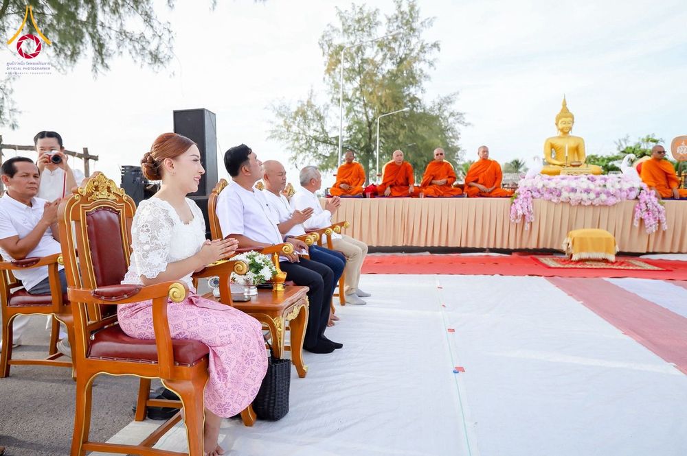 กลุ่มประชาชนนั่งพนมมือร่วมพิธีตักบาตรพระสงฆ์ริมชายหาด