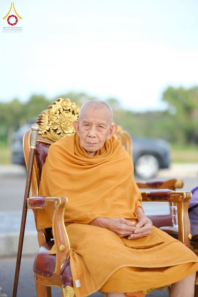 พระภิกษุสงฆ์นั่งบนเก้าอี้ไม้แกะสลักสีทองในอิริยาบถสงบ