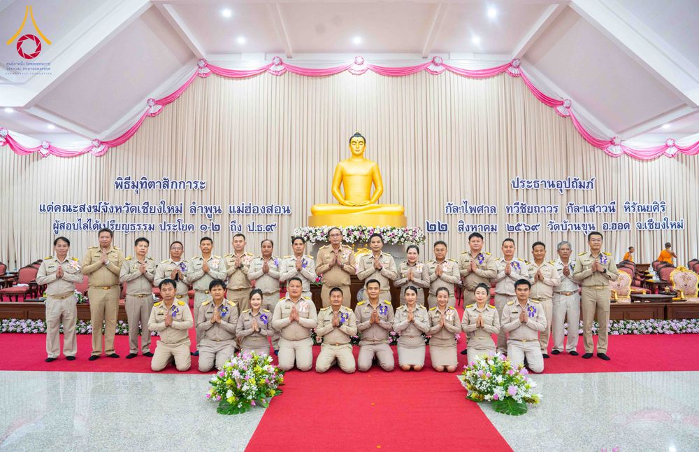 กลุ่มบุคคลยืนและนั่งเรียงแถวถ่ายภาพร่วมกันหน้าพระพุทธรูปในพิธีมุทิตาสักการะมหาเปรียญธรรม