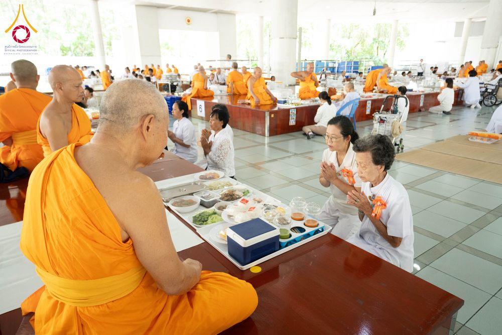 พระภิกษุสงฆ์และพุทธศาสนิกชนในชุดขาวร่วมพิธีถวายภัตตาหารภายในหอฉัน